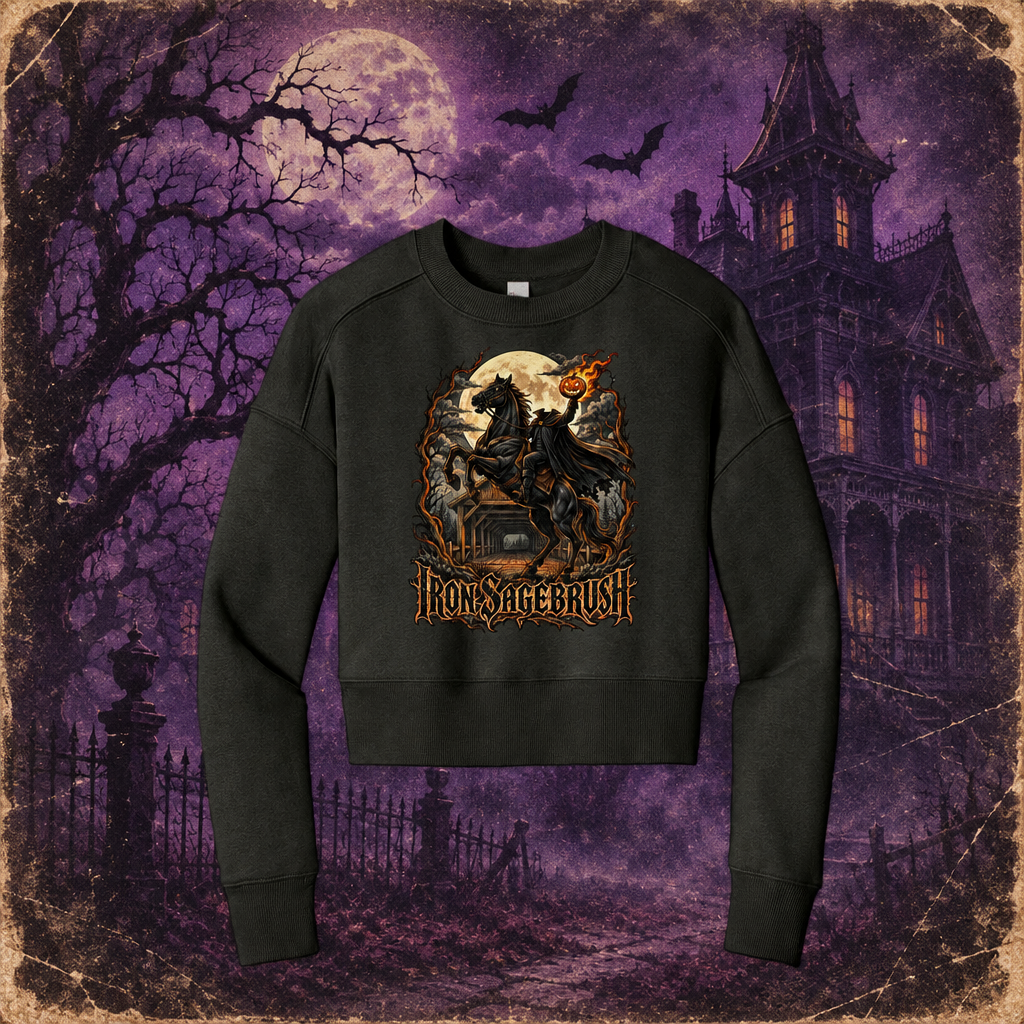 A black crewneck sweatshirt featuring a detailed graphic of a gothic knight on a horse in front of a full moon, with the text 'IRON SAGEBRUSH' below. The sweatshirt is displayed against a spooky purple Halloween-themed background with a haunted house, bare trees, and bats.