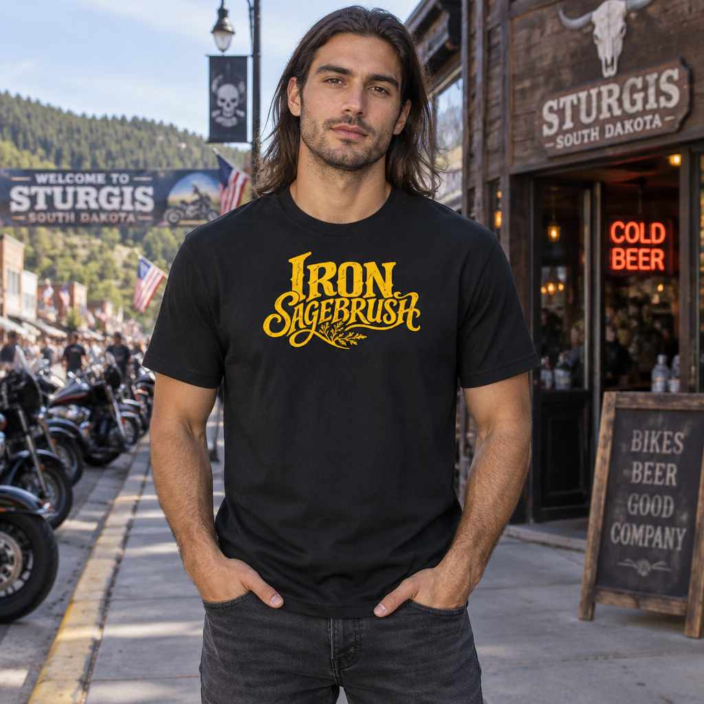 Model wearing a black Iron Sagebrush Vintage Logo T-Shirt with yellow chest lettering on a motorcycle-lined street.