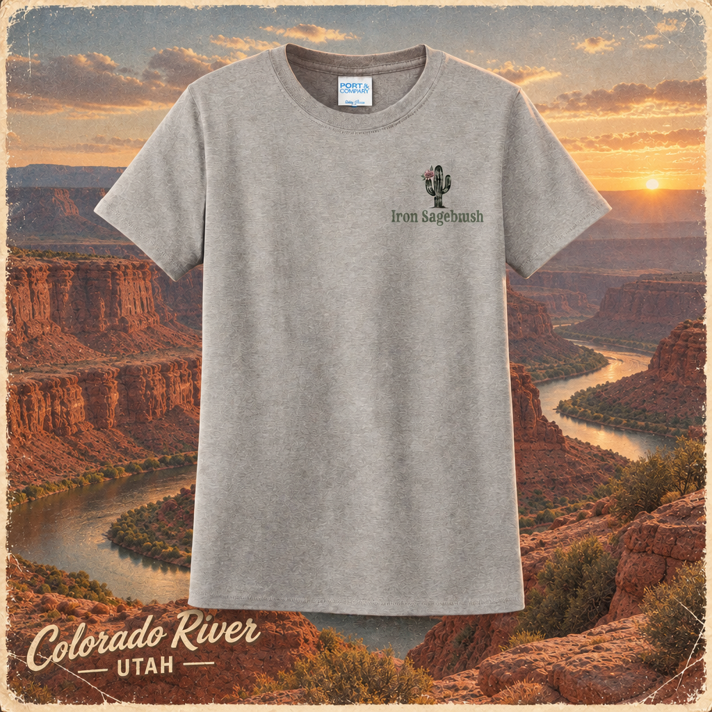A heather gray short-sleeve t-shirt with a small 'Iron Sagebrush' cactus graphic on the left chest, displayed against a scenic background of the Colorado River canyon at sunset.