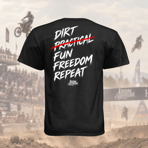 A black short-sleeve t-shirt shown from the back, featuring a white and red graphic print that reads 'DIRT PRACTICAL FUN FREEDOM REPEAT' with an 'Iron Sports' logo underneath, set against a motocross track background.