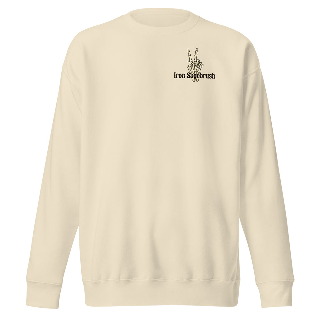 A cream-colored crewneck sweatshirt with a small black graphic on the left chest featuring a hand making a peace sign and the text 'Iron Suckbrush'.