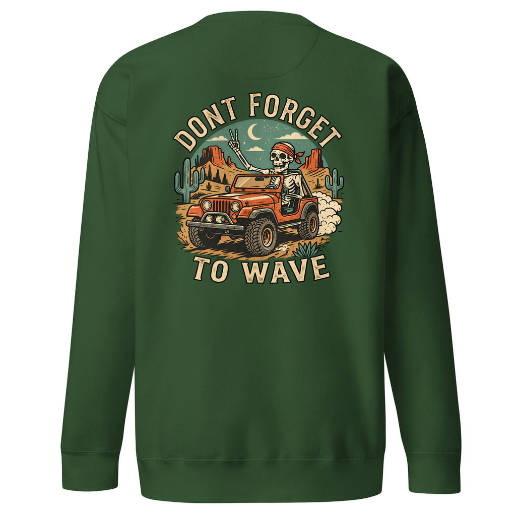 A dark green crewneck sweatshirt shown from the back, featuring a large graphic print of a skeleton driving an orange jeep through a desert landscape under a crescent moon, with the text 'DONT FORGET TO WAVE'.